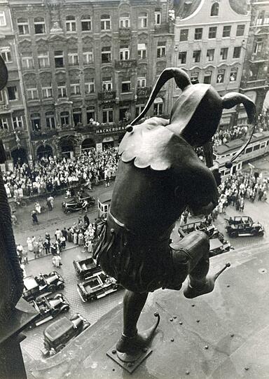 1933/34: Der Blick über die Schulter aus dem Glockenspiel zeigt noch die alte, weiter in den Marienplatz reichende Baulinie der gegenüberliegenden Gebäude.