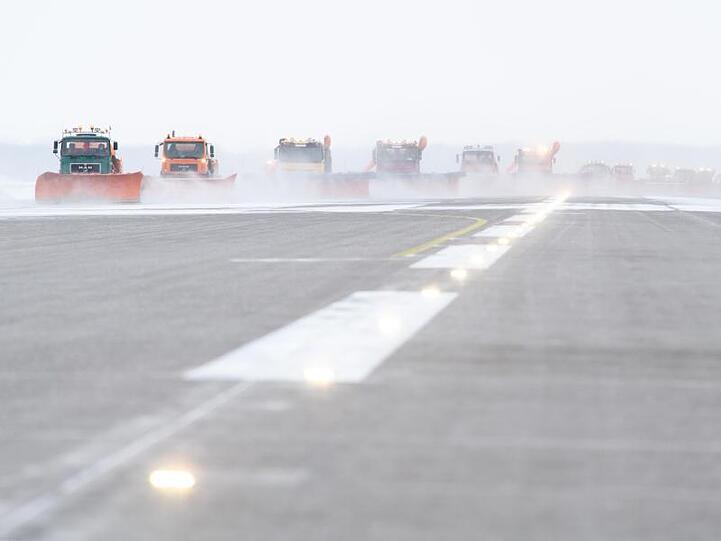 Auf breiter Front: Versetzt fahrende Räumfahrzeuge befreien die Startbahn am Münchener Flughafen vom Schnee.