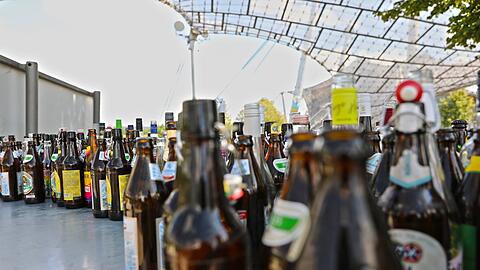 Leere Bierflaschen stehen im Olympiapark. Brauer beklagen eine zu geringe Rückgabe von Leergut.