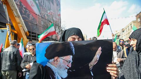 Eine Trauernde h&auml;lt beim Begr&auml;bnis des von Israel get&ouml;teten Generalsekret&auml;rs des iranischen Sicherheitsrats, Ali Laridschani, ein Bild des ebenfalls get&ouml;teten Obersten F&uuml;hrers Ajatollah Ali Chamenei in die H&ouml;he.