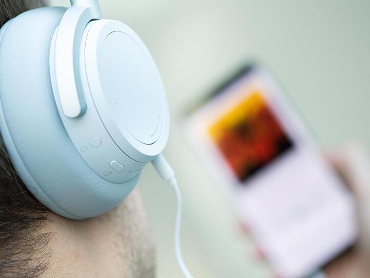 Ein junger Mann hört auf seinem Smartphone einen Podcast.
