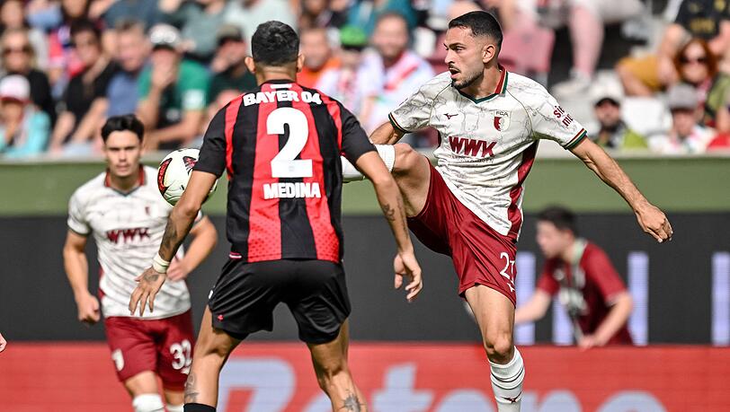 Leverkusens Facundo Medina (links) und Arijon Ibrahimovic vom FC Augsburg kämpfen um den Ball. Leverkusens Facundo Medina (links) und Arijon Ibrahimovic vom FC Augsburg kämpfen um den Ball.