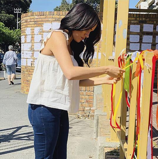 Herzogin Meghan bindet als Zeichen ihrer Anteilnahme eine Schleife an das Denkmal einer südafrikanischen Studentin, die an diesem Ort in Kapstadt ermordet wurde.
