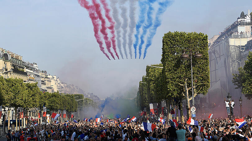 16.07.2018: Nachdem die französische Nationalmannschaft am Tag zuvor die Weltmeisterschaft gewonnen hatte, wird sie von den Fans in Paris empfangen. Bei der Willkommensfeier ist Rauch in den Farben der Tricolore, den Farben der französischen Flagge, über den Champs-Élysées zu sehen.