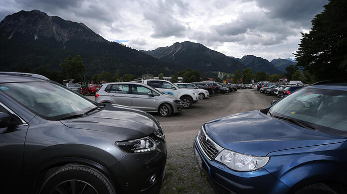 Autos von Ausflüglern stehen am Ortseingang von Oberstdorf auf einem Parkplatz.