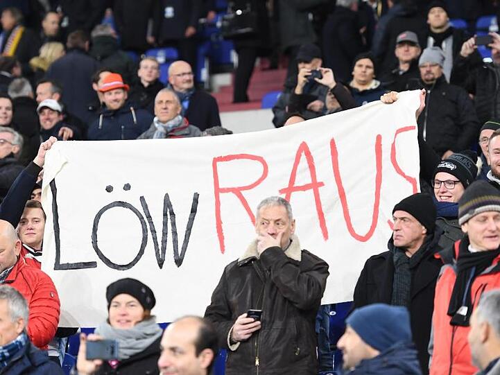 Zwei Fans unter den vielen Zuschauern halten ein Transparent mit der Aufschrift "Löw Raus".