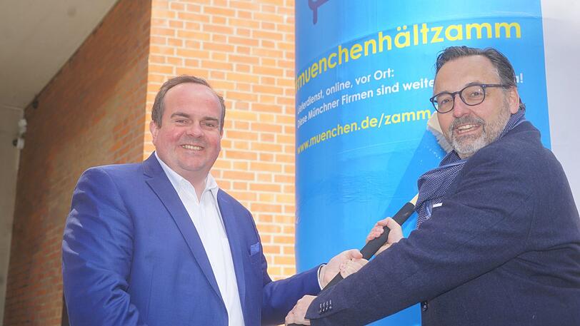 Wirtschaftsreferent Clemens Baumgärtner (links) und Kulturreferent Anton Biebl plakatieren eine Litfaßsäule. Die Plakate werden bald in der ganzen Stadt zu sehen sein.