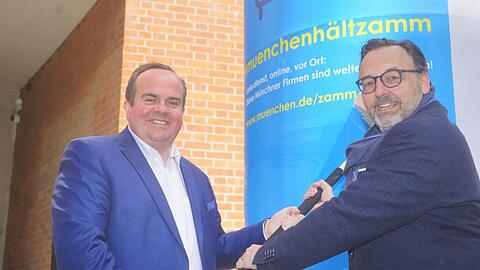 Wirtschaftsreferent Clemens Baumgärtner (links) und Kulturreferent Anton Biebl plakatieren eine Litfaßsäule. Die Plakate werden bald in der ganzen Stadt zu sehen sein.