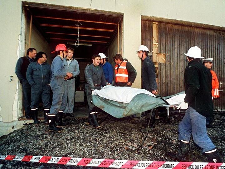 Polizei und Feuerwehrleute tragen am 5. Oktober 1994 die tot aufgefundenen Sektenmitglieder aus dem Haus in Cheiry im Kanton Freiburg. Hier starben zehn Männer, zwölf Frauen und ein Kind.