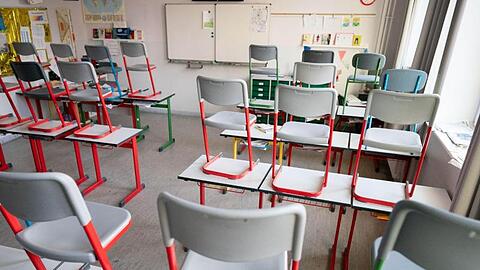 Stühle stehen in einem Klassenzimmer auf den Tischen.