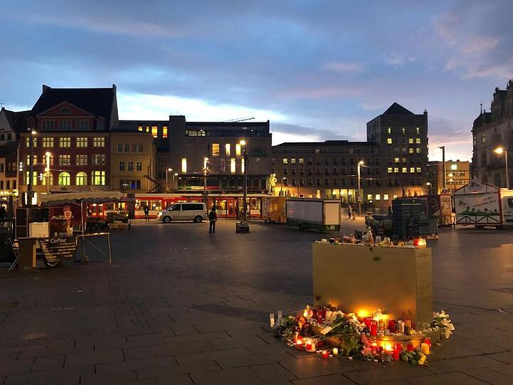 Blumen und Kerzen liegen auf dem Marktplatz in Halle.