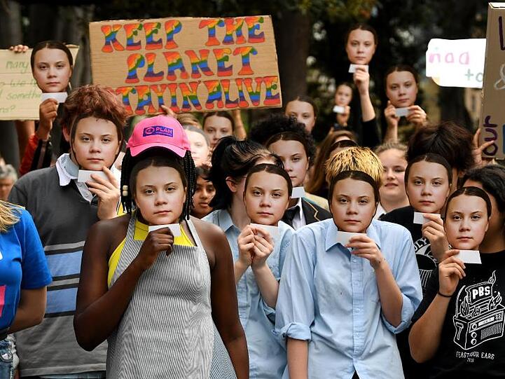 Greta Thunberg überall: Teilnehmer der Demonstration in Melbourne halten Masken mit dem Gesicht der schwedischen Umweltaktivistin vor ihre Gesichter.