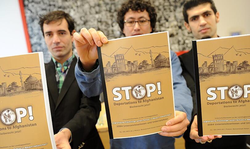 Die afghanischen Flüchtlinge Jamal Nasir (l-r), Javad Saberi und Matin Ameri halten im Bayerischen Landtag eine Petition in den Händen.