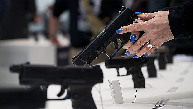 Eine Besucherin der Fachmesse für Jagd, Schießsport, Outdoor und Sicherheit IWA OutdoorClassics hält eine Handfeuerwaffe (PPQ) des deutschen Herstellers Walther in den Händen.