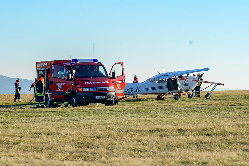 Feuerwehrleute stehen nach dem Flugunfall neben einem Sportflugzeug.