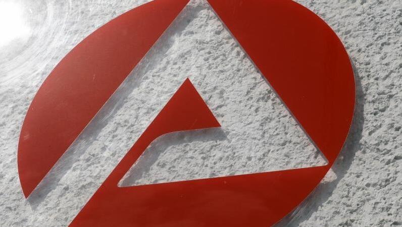 Auf dem Schild der Agentur für Arbeit spiegelt sich die Sonne. Foto: Bernd Wüstneck/dpa/Archivbild