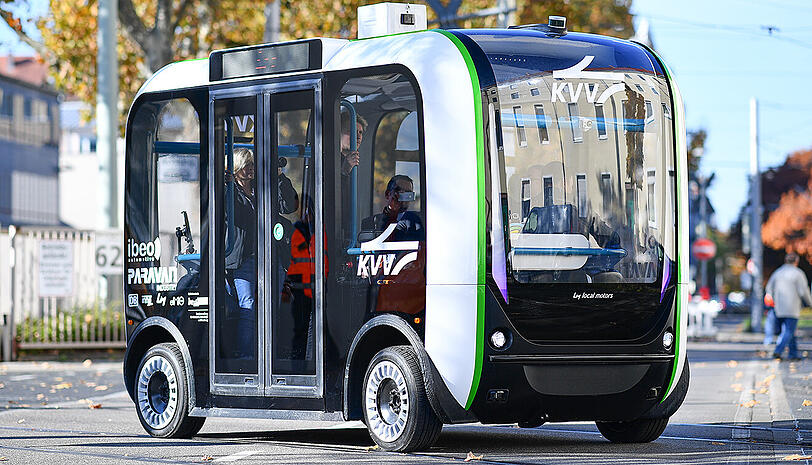 Ein autonom fahrender Elektro-Minibus im Testbetrieb überquert in Karlsruhe (Baden-Württemberg) vor dem Gebäude des Karlsruher Verkehrsverbunds eine Straße.