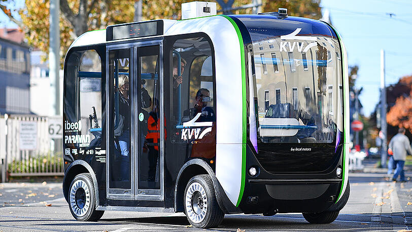 Ein autonom fahrender Elektro-Minibus im Testbetrieb überquert in Karlsruhe (Baden-Württemberg) vor dem Gebäude des Karlsruher Verkehrsverbunds eine Straße. Ein autonom fahrender Elektro-Minibus im Testbetrieb überquert in Karlsruhe (Baden-Württemberg) vor dem Gebäude des Karlsruher Verkehrsverbunds eine Straße.