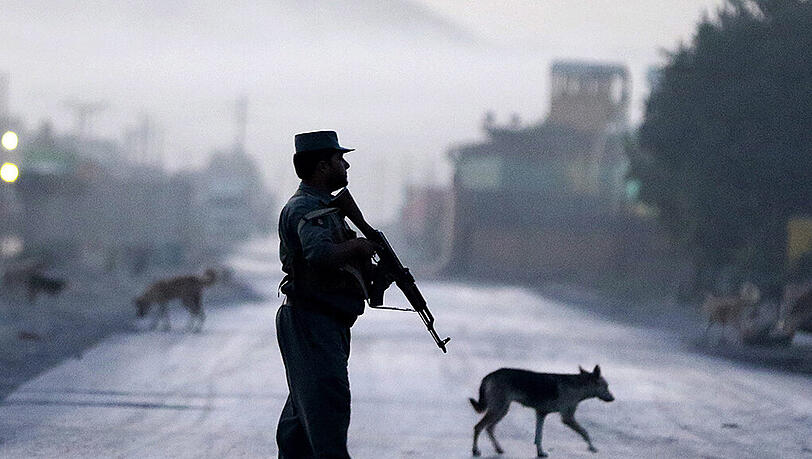 Ein afghanischer Polizist bewacht eine Straße in Kabul, die zu der Unterkunft führt, in der die Gäste des Hotels untergebracht sind, das jüngst von Taliban angegriffen wurde.