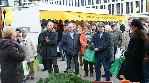 Zahlreiche Besucher lauschen auf dem Rainer-Werner-Fassbinder-Platz einer Rede zur Eröffnung des neuen Bauernmarktes.