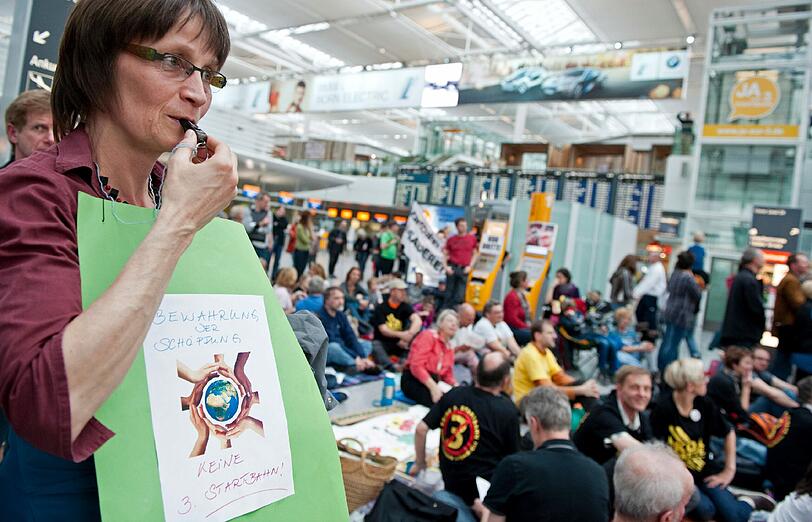 Demonstranten sitzen am Samstag (24.03.2012) am Terminal 2 des Münchner Flughafens auf Picknickdecken. Der Bund Naturschutz und das Aktionsbündnis AufgeMUCkt haben zum Protest-Picknick aufgerufen, um gegen den Bau einer dritten Startbahn am Münchner Flughafen zu demonstrieren.