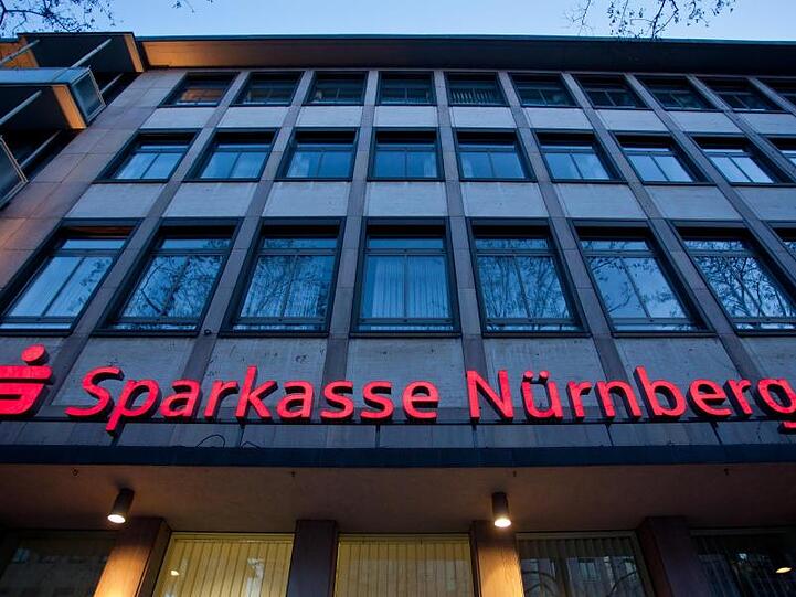 Das beleuchtete Logo einer Sparkasse in Nürnberg. Foto: Daniel Karmann/dpa/Archivbild