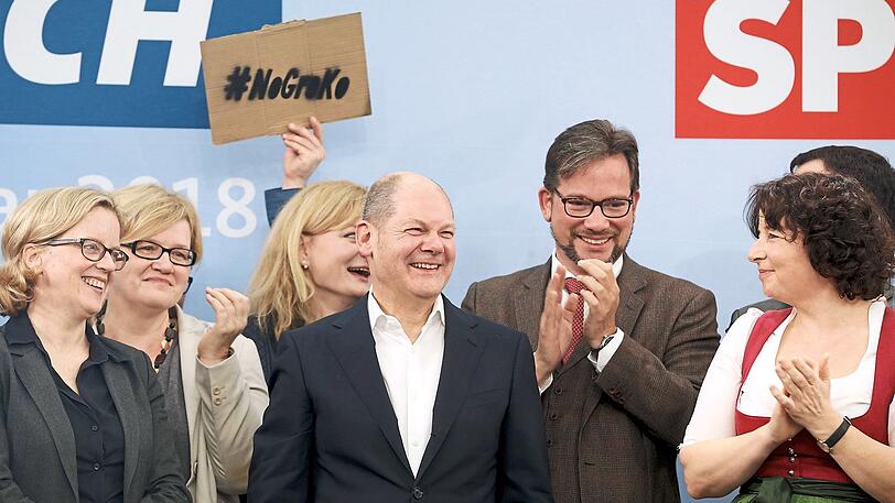 Das ganze Dilemma der SPD: Während unter anderem Natascha Kohnen (l.) und Florian Pronold (3.v.r.) den Auftritt von Olaf Scholz (Mitte) beklatschen, fordert ein Juso im Hintergrund, keine erneute Große Koalition mit der Union einzugehen.  - Linkes Bild: Die SPD-Granden beim Prosit - mit Weißbieren, die mit Blick auf die Schaumkrone wohl schon länger gestanden sind.
