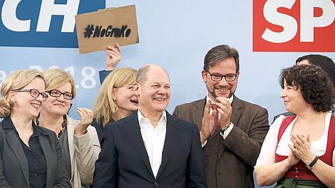 Das ganze Dilemma der SPD: Während unter anderem Natascha Kohnen (l.) und Florian Pronold (3.v.r.) den Auftritt von Olaf Scholz (Mitte) beklatschen, fordert ein Juso im Hintergrund, keine erneute Große Koalition mit der Union einzugehen.  - Linkes Bild: Die SPD-Granden beim Prosit - mit Weißbieren, die mit Blick auf die Schaumkrone wohl schon länger gestanden sind.