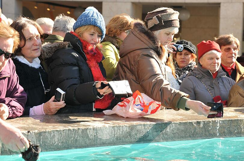 Soll Geld bringen: Münchner Bürger waschen am Aschermittwoch im Fischbrunnen ihren Geldbeutel aus.