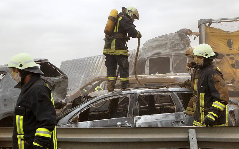 Feuerwehrleute sind am Freitag auf der Autobahn A19 bei Kavelstorf in der Nähe von Rostock bei einer Massenkarambolage im Einsatz. Bei einem Sandsturm fuhren in beiden Fahrtrichtungen Dutzende Fahrzeuge und LKW ineinander und brannten teilweise aus.