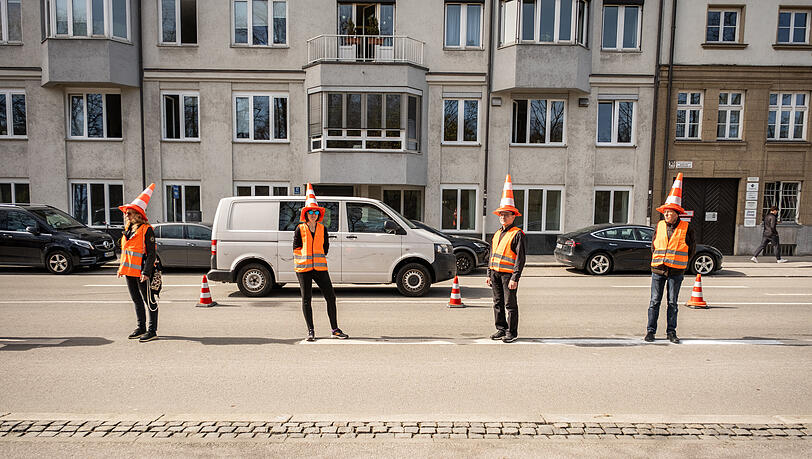 Radaktivisten haben sich mit Warnwesten und Lenkkegel auf dem Kopf als "lebende Protected Bike Lane" auf die Straße gestellt. Radaktivisten haben sich mit Warnwesten und Lenkkegel auf dem Kopf als "lebende Protected Bike Lane" auf die Straße gestellt.