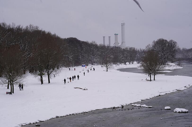 Weiße Pracht: Spaziergänger laufen am schneebedeckten Isarufer entlang.