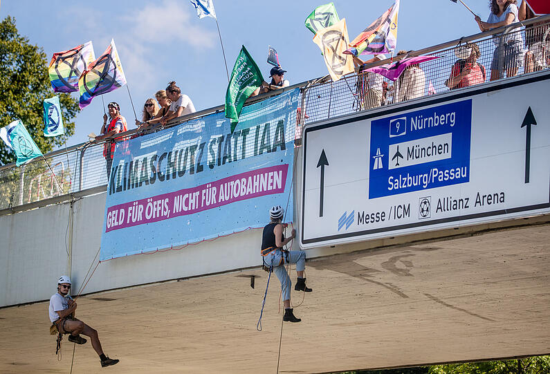 Klimaaktivisten der "Extinction Rebellion" München seilen sich am Montag am Georg-Brauchle-Ring über der Fahrbahn ab.