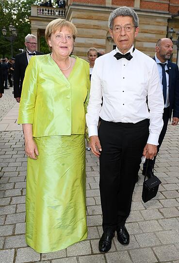 Für das Grusel-Outfit des Abends sorgte Angela Merkel (hier mit Joachim Sauer). In ihrem grünen Kleid wirkt sie wie ein in Plastik verpacktes Apfelbonbon.
