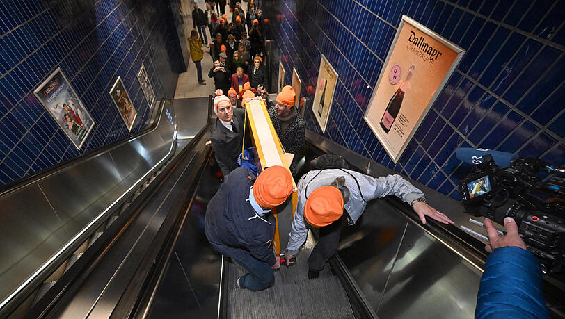 Das Schild der Lach- und Schießgesellschaft wird von Mitgliedern der Münchner Lach- und Schießgesellschaft auf einem Leiterwagen auf einer Rolltreppe zur S-Bahn Station Marienplatz gebracht. Die Münchner Lach- und Schießgesellschaft zieht mit U-Bahn und S-Bahn von der Haimhauserstraße zur Fat Cat (Alter Gasteig) am Rosenheimer Platz um. Das Schild der Lach- und Schießgesellschaft wird von Mitgliedern der Münchner Lach- und Schießgesellschaft auf einem Leiterwagen auf einer Rolltreppe zur S-Bahn Station Marienplatz gebracht. Die Münchner Lach- und Schießgesellschaft zieht mit U-Bahn und S-Bahn von der Haimhauserstraße zur Fat Cat (Alter Gasteig) am Rosenheimer Platz um.