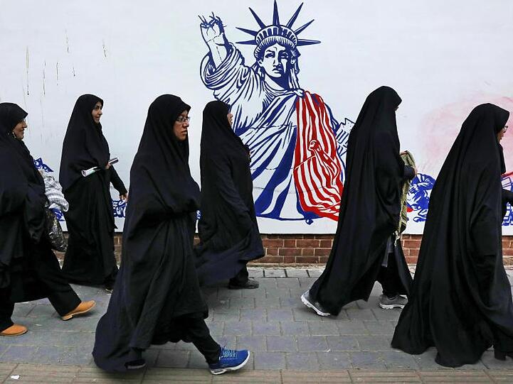 Die Teilnehmerinnen einer Trauerzeremonie für den getöteten General Soleimani gehen auf ihrem Heimweg an der satirischen Zeichnung einer verstümmelten Freiheitsstatue vorbei.