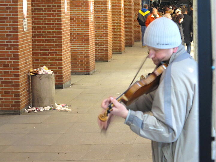 "Ein Straßenmusiker scheint eine Romanze für einen überfüllten Abfalleimer zu spielen..."