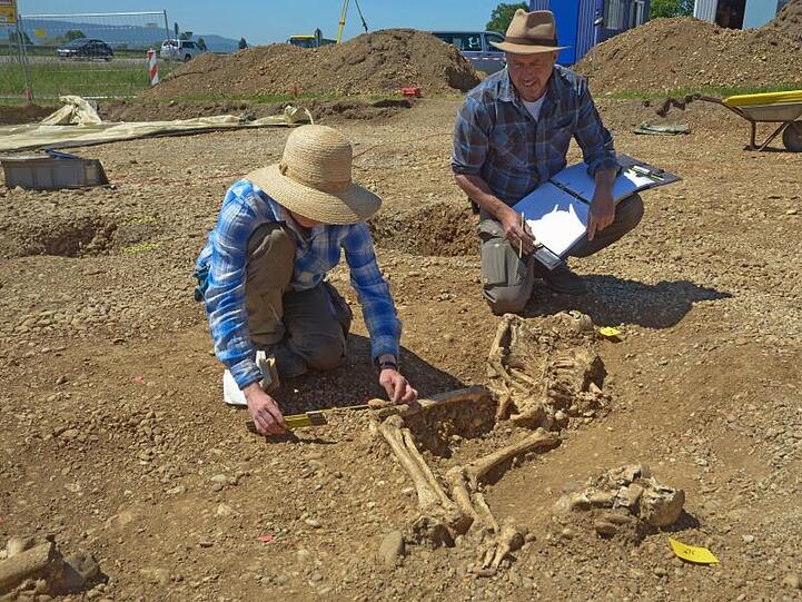 Die Archäologen Fiona Vernon (l) und Jürgen Hald (r) dokumentieren menschliche Skelettreste. Foto: Landratsamt/Landratsamt Konstanz/dpa/Archivbild