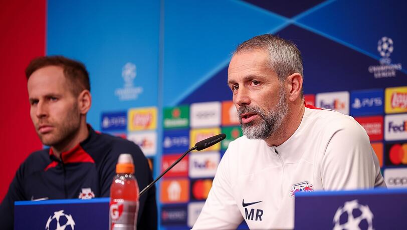Leipzigs Trainer Marco Rose sitzt neben Torwart Peter Gulacsi bei der Pressekonferenz auf dem Podium.