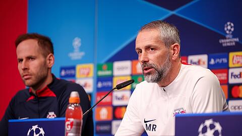 Leipzigs Trainer Marco Rose sitzt neben Torwart Peter Gulacsi bei der Pressekonferenz auf dem Podium.
