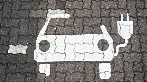 Ein Symbol für E-Autos ist auf einem Parkplatz zu sehen.