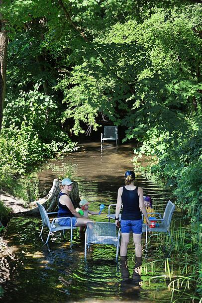 Das Freibadbächl fließt leise durch den Rosengarten. Im Sommer stehen die metallenen Stühle, die sonst am Weg oder auf der Wiese stehen, im Wasser – hervorragend, um die Füße abzukühlen und mit den Kindern zu planschen. Das Freibadbächl fließt leise durch den Rosengarten. Im Sommer stehen die metallenen Stühle, die sonst am Weg oder auf der Wiese stehen, im Wasser – hervorragend, um die Füße abzukühlen und mit den Kindern zu planschen.