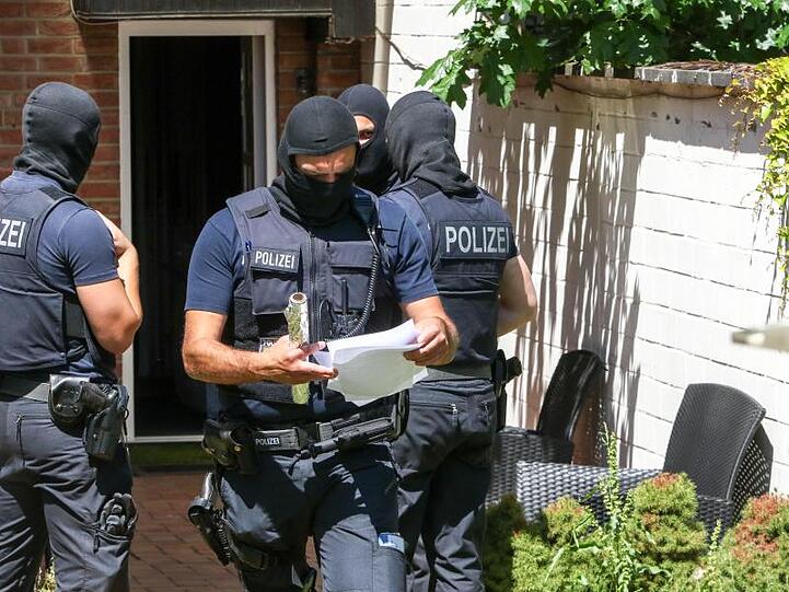 Bundespolizisten stehen vor einer Wohnung. Foto: Ralf Roeger