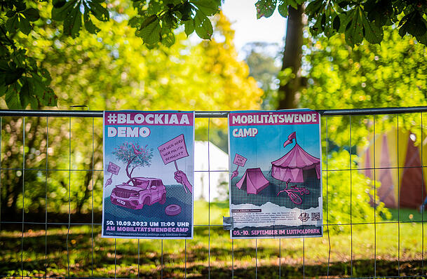 An einem Zaun am Mobilitätswendecamp 2023 befestigte Plakate.
