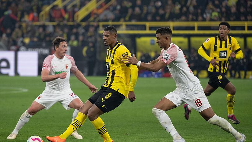 Dortmunds Sebastien Haller und Felix Uduokhai von Augsburg versuchen an den Ball zu kommen.