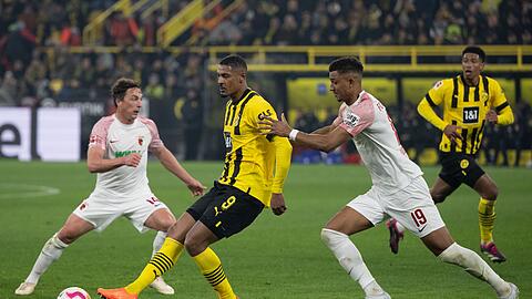Dortmunds Sebastien Haller und Felix Uduokhai von Augsburg versuchen an den Ball zu kommen.