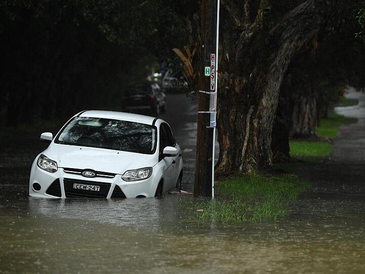 Ein Auto steht in einer überfluteten Straße in Sydney. Schwere Unwetter haben weite Teile Australiens heimgesucht.