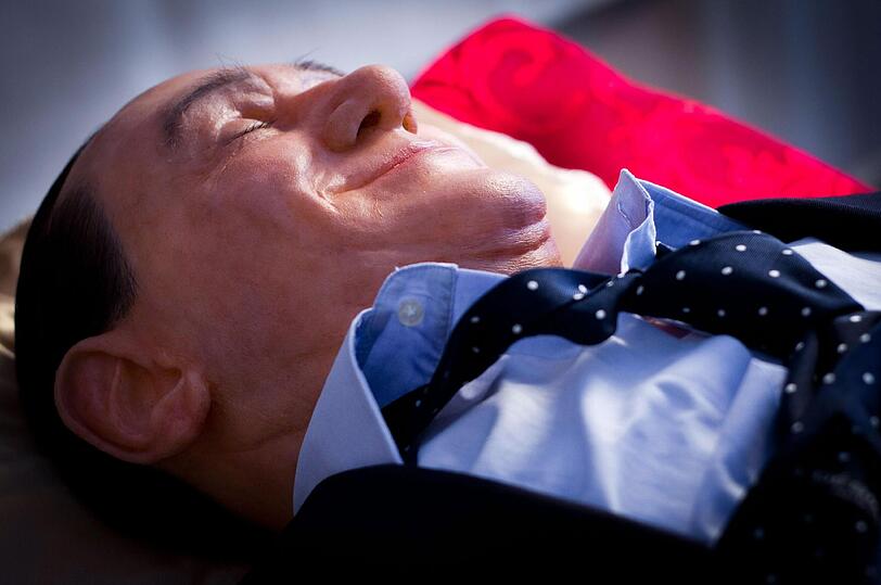Wie ein Heiliger - oder wie Mao und Lenin? - Eine Wachsfigur von Silvio Berlusconi aufgebahrt in einem Glassarg.
