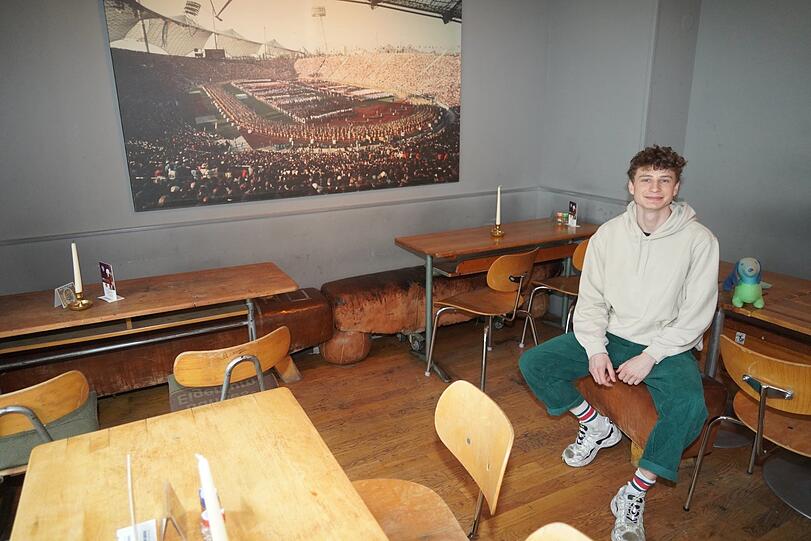 Dennis arbeitet im München 72. Bevor die ersten Gäste kommen, nimmt er auch mal auf einem Bock Platz und lacht in die Kamera. Sein Chef möchte nicht aufs Bild.