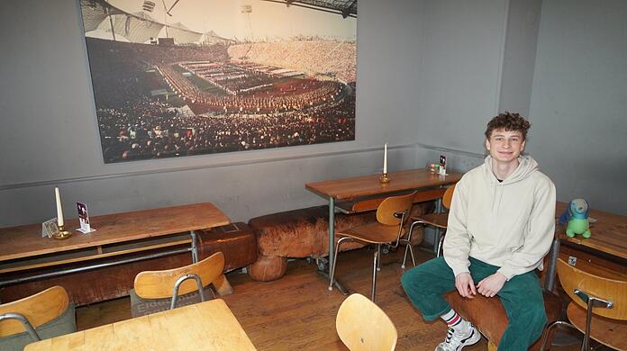 Dennis arbeitet im München 72. Bevor die ersten Gäste kommen, nimmt er auch mal auf einem Bock Platz und lacht in die Kamera. Sein Chef möchte nicht aufs Bild.